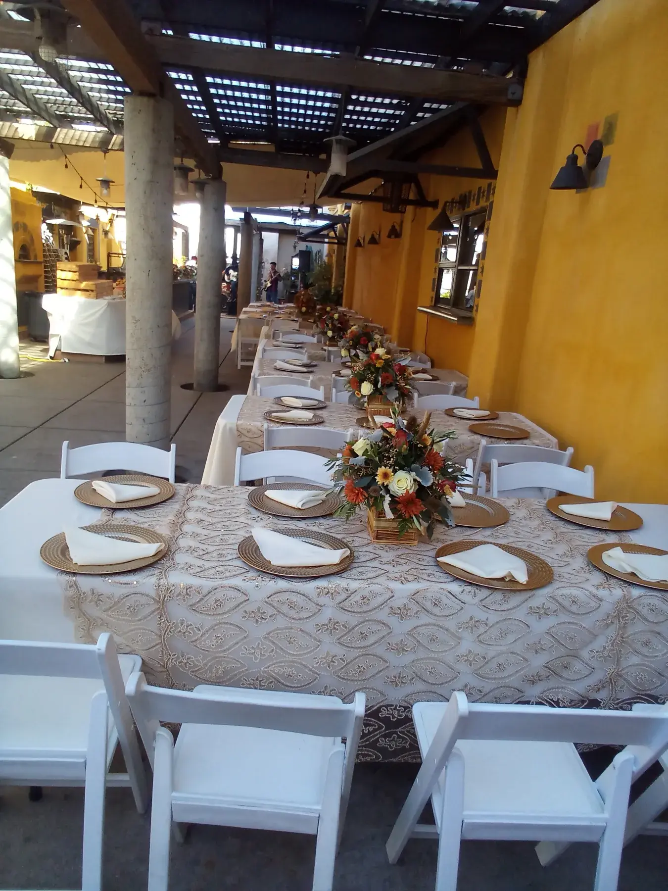 Long formal dining tables arranged beneath the restaurant patio.