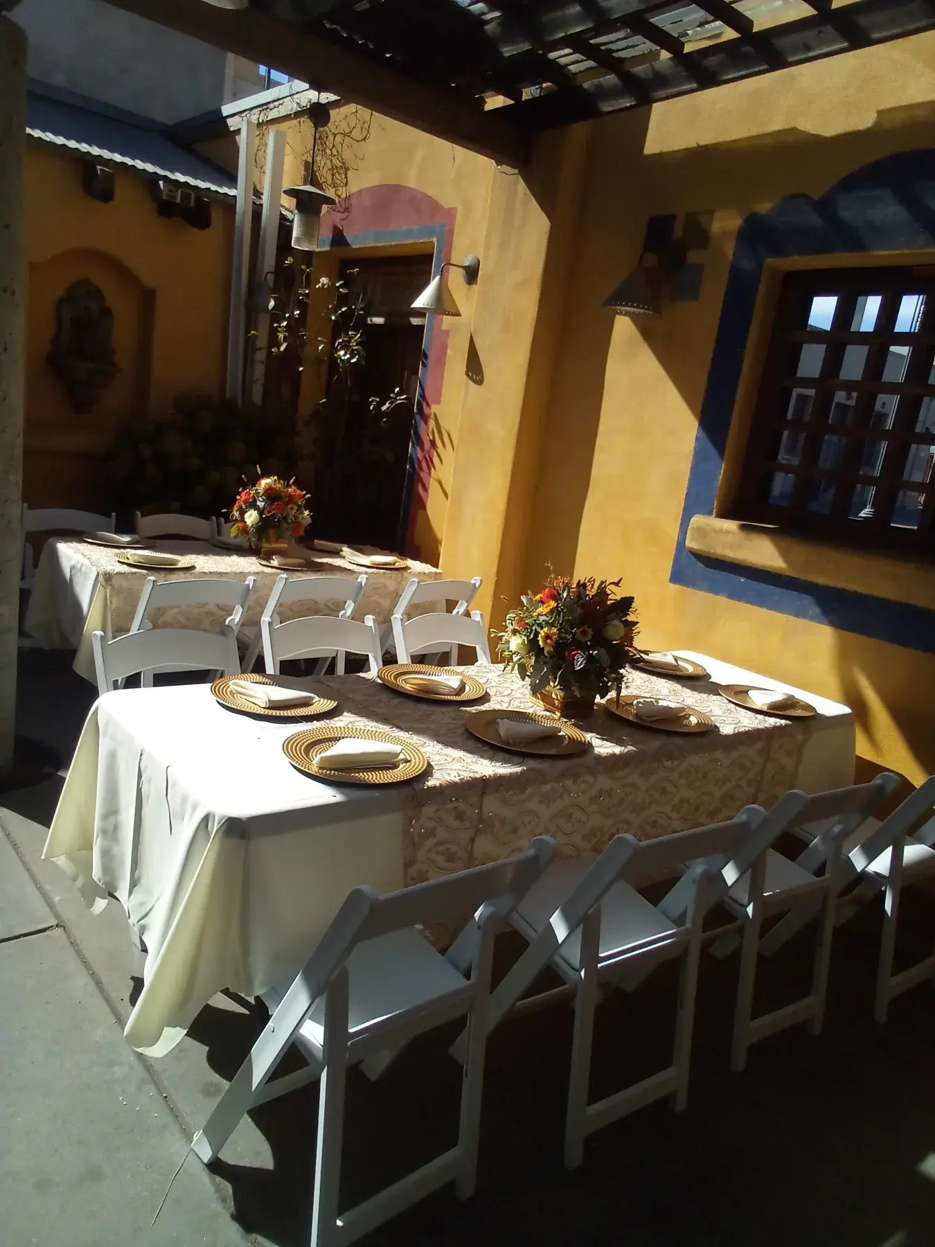 A bright event room prepared with round tables and floral centerpieces.