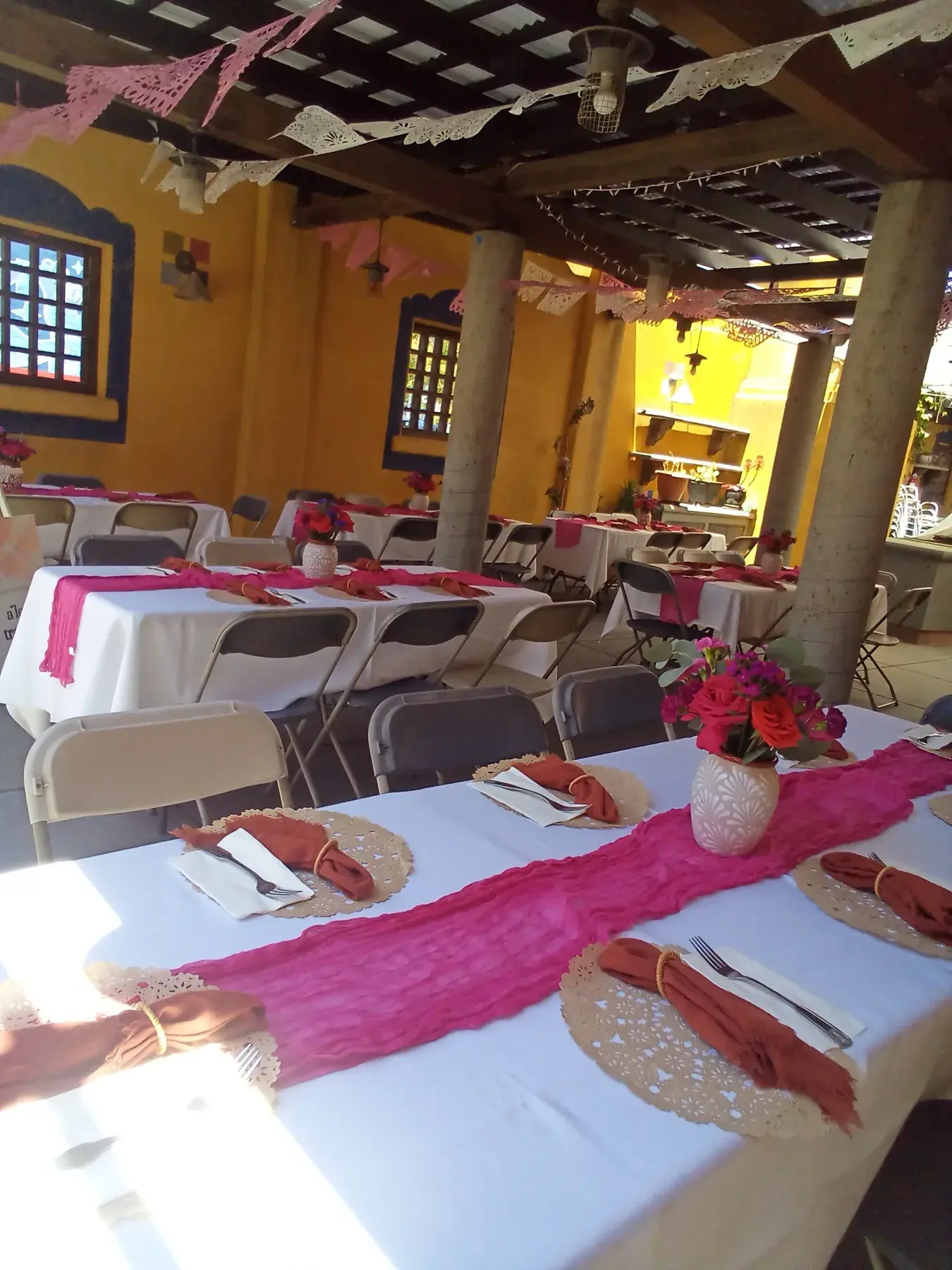 A vibrant pink event table setting with place settings and floral decor.