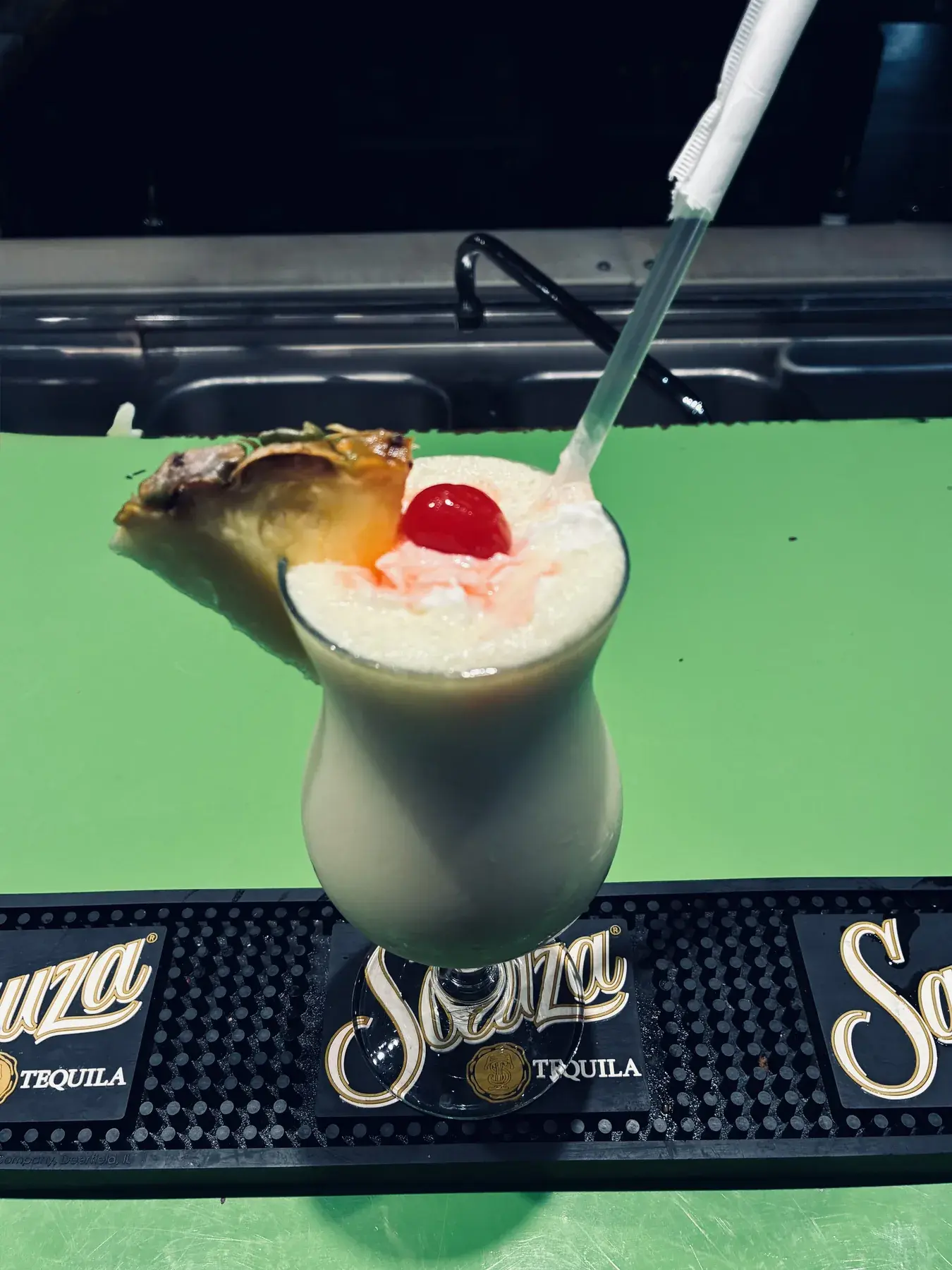A creamy cocktail finished with pineapple and a cherry at the bar.