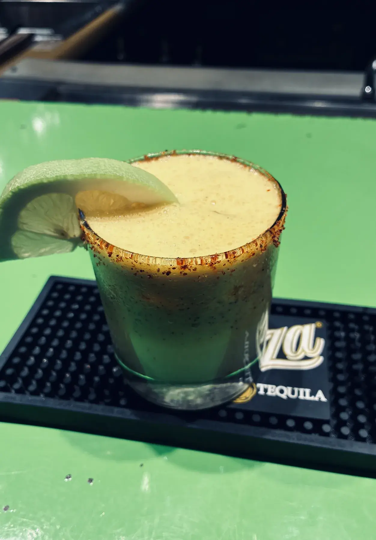 A pale cocktail with a lime wheel and chile-salt rim.